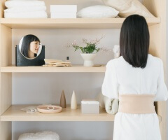 Marie Kondo standing in front of a shelf organizing